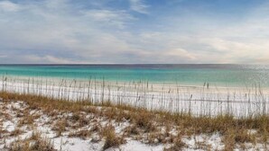 Una spiaggia con acque cristalline turchesi, sabbia bianca e vegetazione rada.