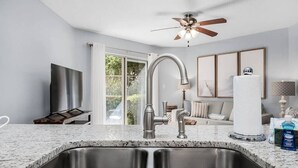 Una cucina moderna con lavello in acciaio inossidabile, ventilatore a soffitto e una grande finestra.