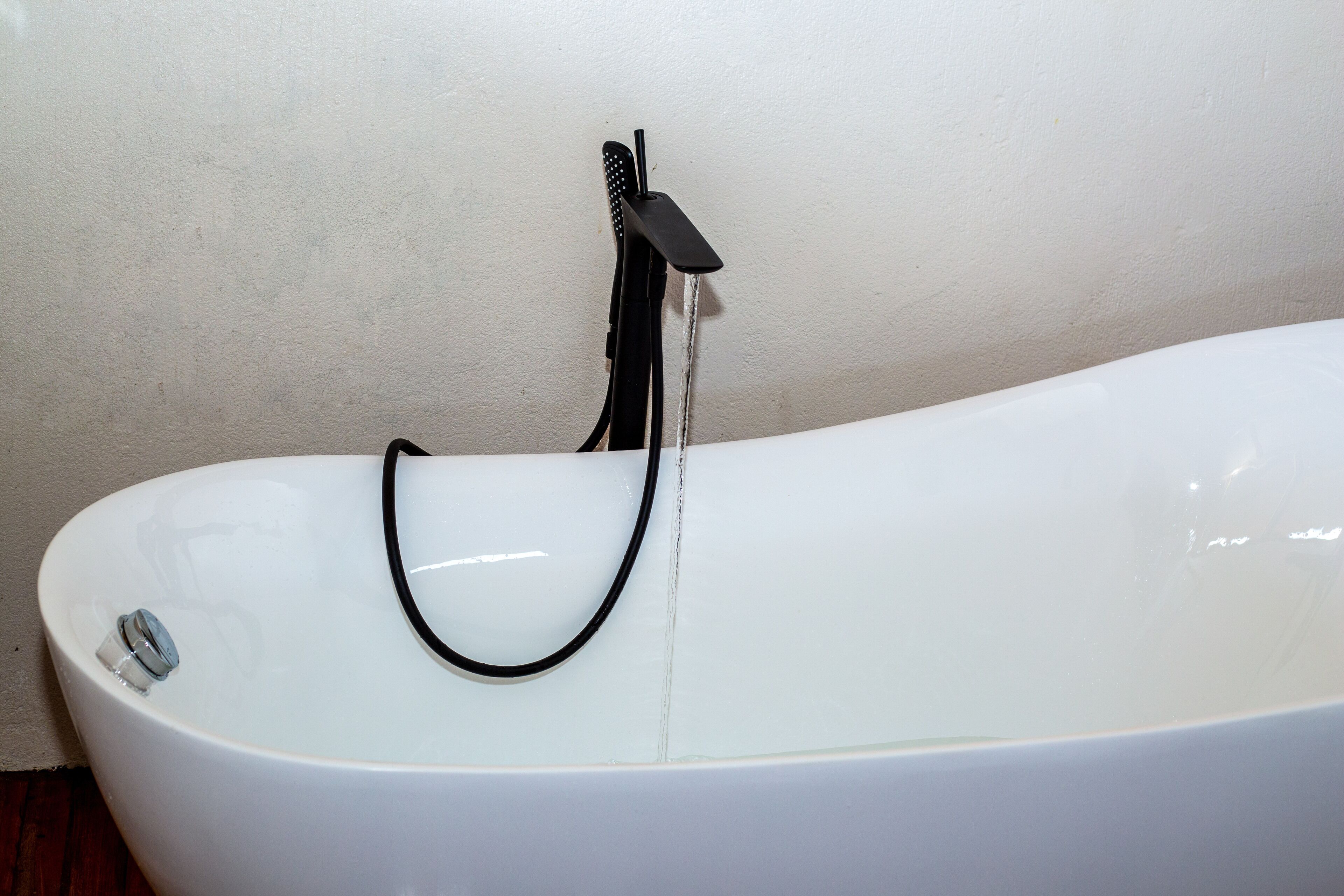 Une baignoire blanche avec un tuyau noir et un robinet.