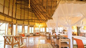 A spacious room with a high ceiling and wooden beams, furnished with wooden furniture and a canopy bed. - Aardvark Safari Lodge (Kasese)