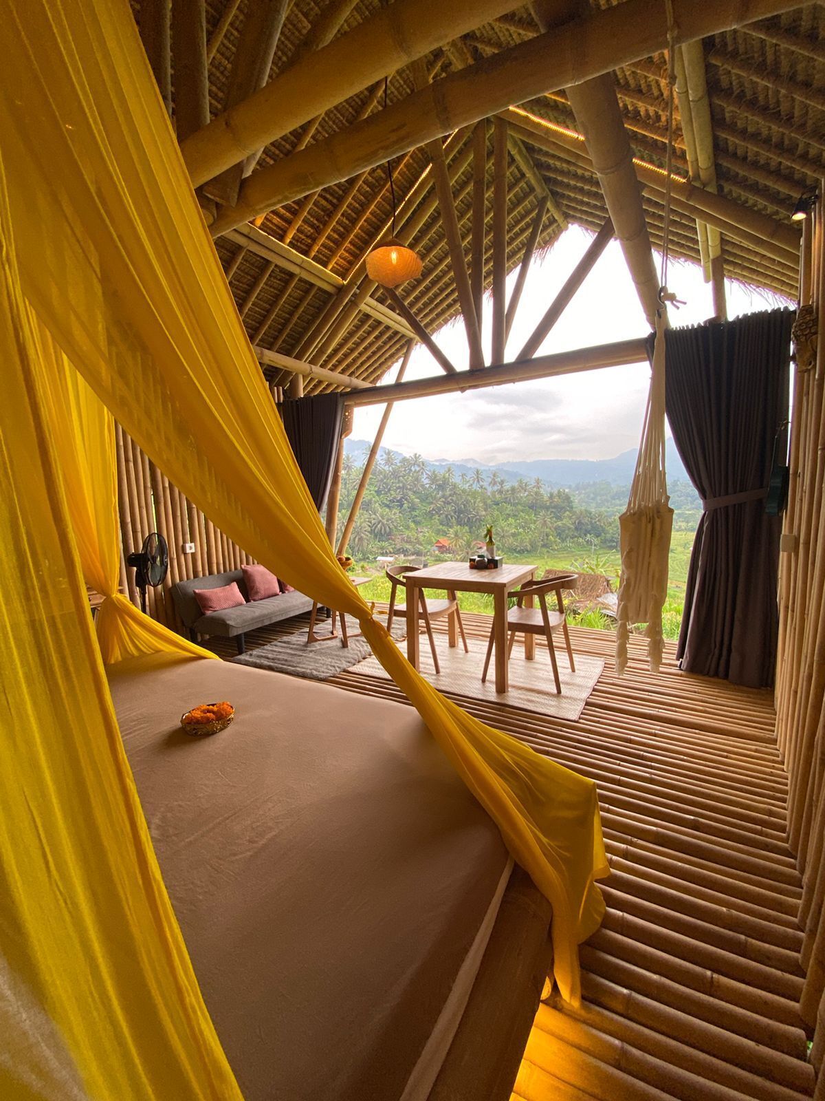 A room with a bed, a small table, and a view of the landscape.