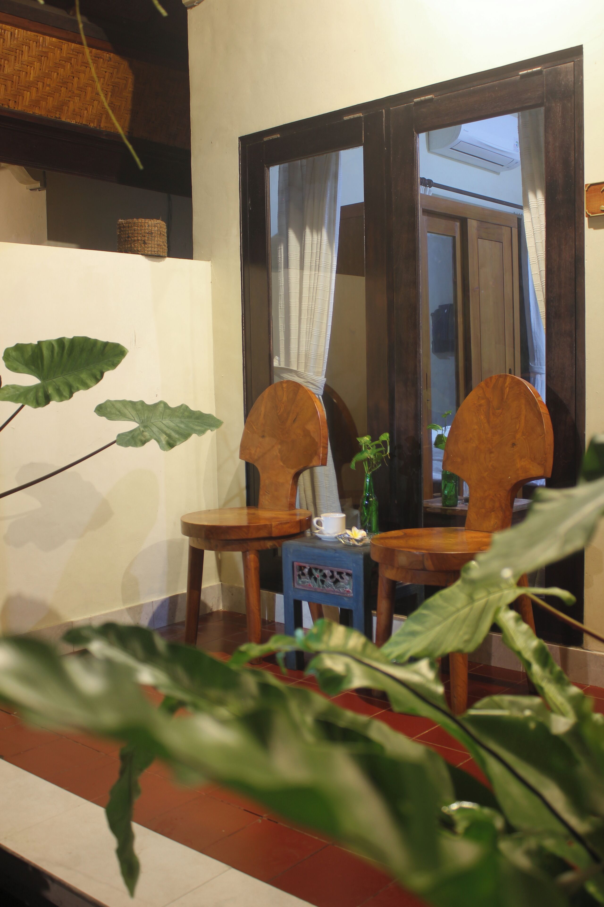 Une pièce avec deux chaises en bois et une petite table, un miroir et une plante en pot.
