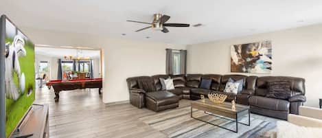 A modern living room with a sectional sofa, a coffee table, and a ceiling fan.
