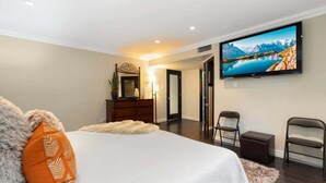 Un dormitorio con cama, televisión, cómoda y espejo.