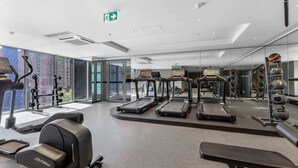 A modern gym with treadmills, weight machines, and a bench.