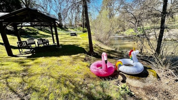 Un parque con un pabellón, bancos, y flamencos y unicornios inflables.
