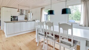 Une cuisine moderne avec des meubles blancs, un plancher en bois et des luminaires suspendus.