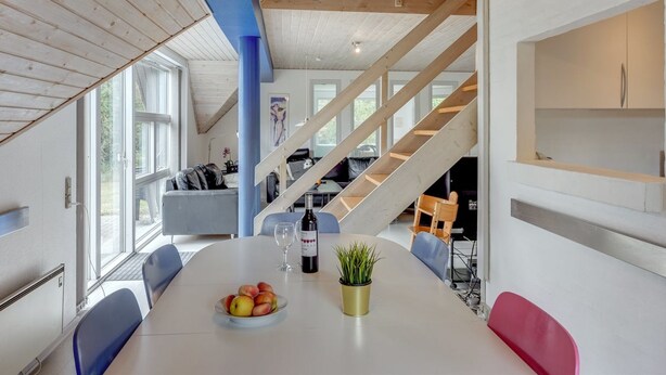 A modern interior with a dining table, chairs, a staircase, and a view of the outdoors. - "Tabithe" - 2.2km from the sea by Interhome (Henne)