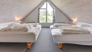 A cozy attic bedroom with two beds, a large window, and wooden ceiling beams. - "Tabithe" - 2.2km from the sea by Interhome (Henne)