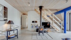 A modern living room with a wood-burning stove, a television, and a staircase. - "Tabithe" - 2.2km from the sea by Interhome (Henne)