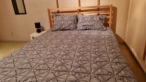 Une chambre à coucher avec une tête de lit en bois, une couvre-lit à motifs et une table de chevet avec une lampe.