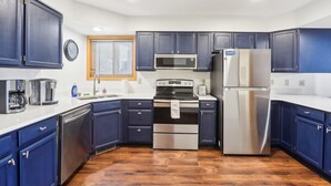 A compact kitchen with dark blue cabinets, stainless steel appliances, and a wooden floor. - Wisconsin Dells Escape - Amazing Views - Pools (Wisconsin Dells)