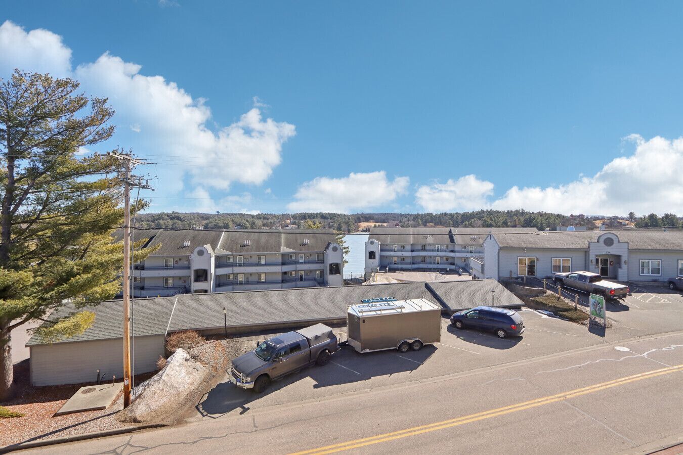 A multi-story hotel with a parking lot, a large truck, and a tree.