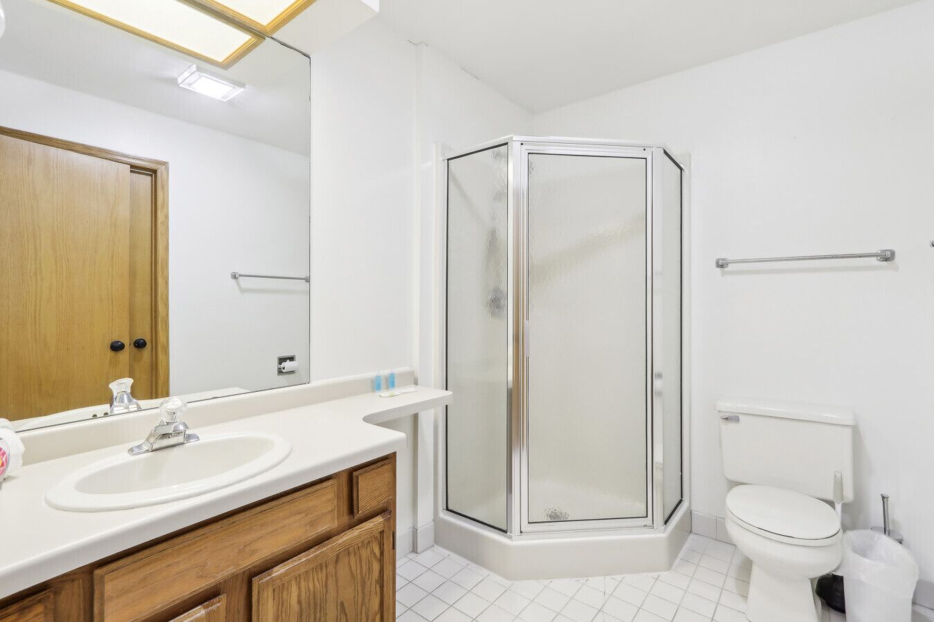 A modern bathroom with a glass shower enclosure, a wooden vanity with a sink, and a toilet.