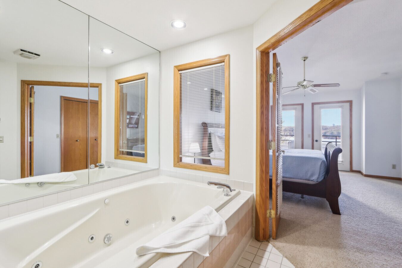 Un baño moderno con una bañera grande, un espejo y ventanas con marco de madera.