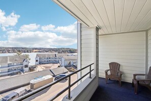 A balcony with a view of a waterfront and buildings. There are two wooden chairs and a metal railing. - Wisconsin Dells Escape - Amazing Views - Pools (Wisconsin Dells)
