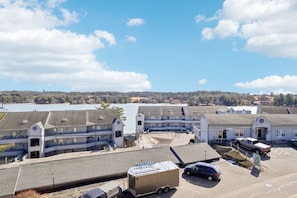 Ett hotell med flera byggnader, en parkeringsplats och utsikt över en vattenyta och ett avlägset landskap.