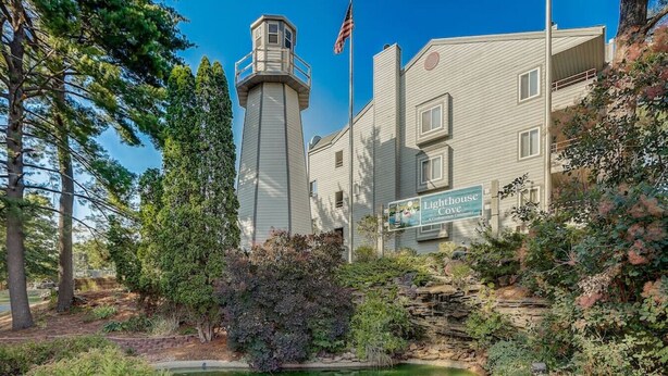 A building with a lighthouse tower, a flag, and a sign reading 'Lighthouse Cove'. - Wisconsin Dells Escape - Amazing Views - Pools (Wisconsin Dells)