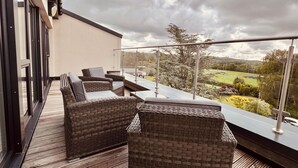 A balcony with wicker furniture and a view of a park. - River View (Preston)
