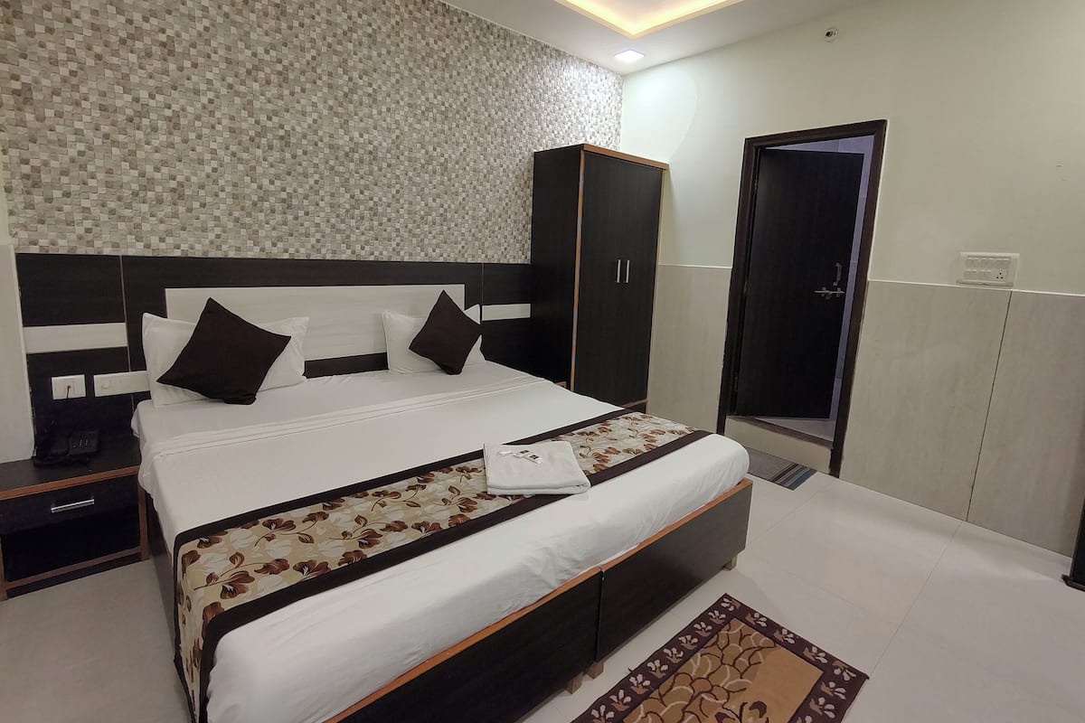 A neatly arranged bedroom with a bed, a wardrobe, a nightstand, and a bedside table.