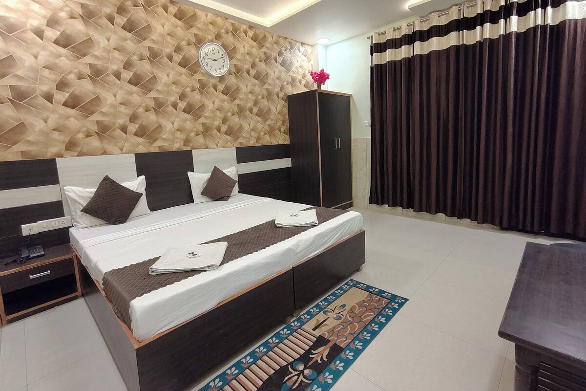 A bedroom with a bed, a wardrobe, a nightstand, a ceiling fan, and a window with curtains.