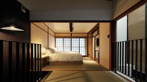 Quarto japonês tradicional com chão de tatame, futon baixo e portas deslizantes.