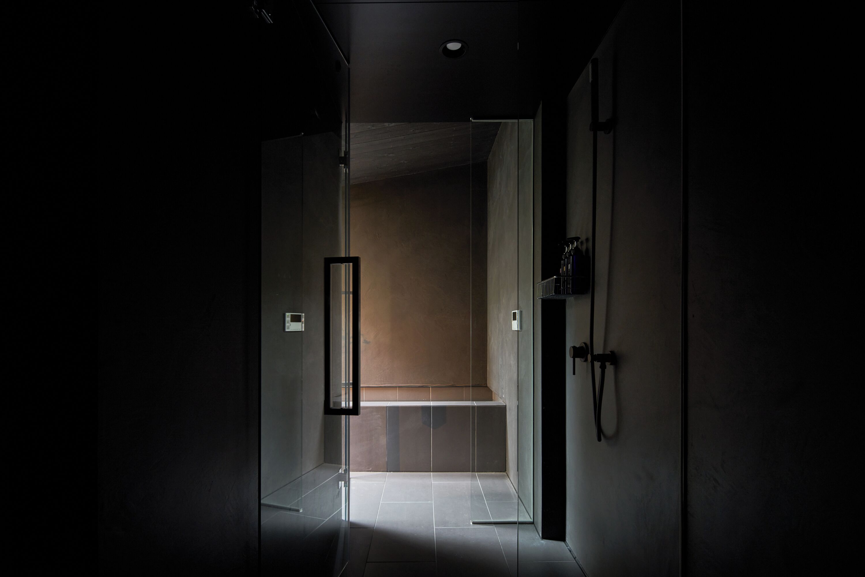 A modern bathroom with a glass shower enclosure, a bench, and a towel rack.