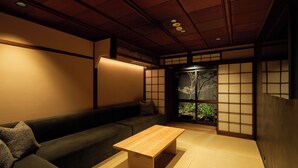 Um quarto japonês tradicional com tatames, uma mesa de madeira baixa, um sofá e biombos shoji.