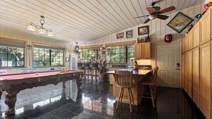 A pool table, wooden bar, and bar stools in a room with wooden paneling and a ceiling fan. - Hot Tub Hideaway - Game Room - Near Kirkwood (West Point)