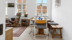 A bright, open-plan living space with a dining area, a wooden table, and a cozy seating arrangement.
