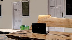 A wooden table with a laptop, a green basket, and a wooden bench.