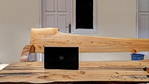 A wooden table with a laptop on it, a blue basket, and a door in the background.