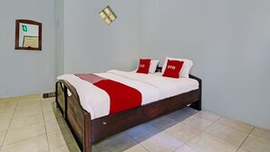 A neatly made bed with a wooden frame, white bedding, and red pillows.