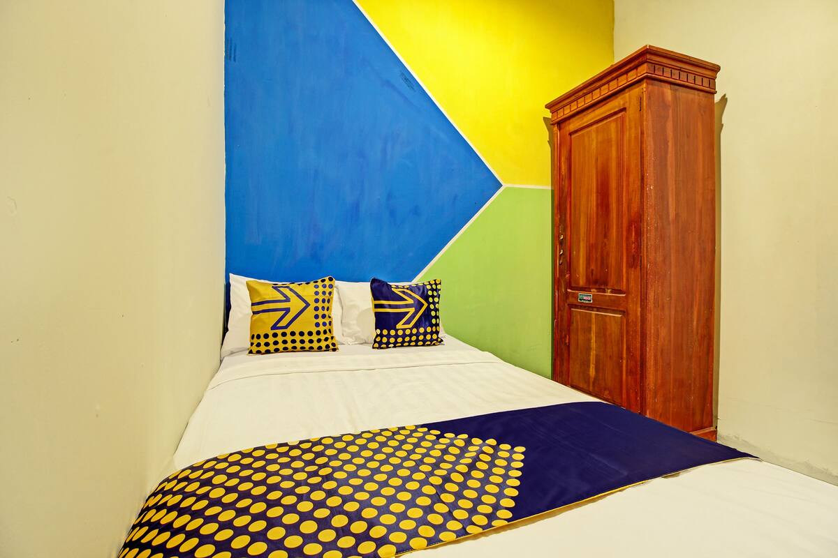 A bed with a blue and yellow polka dot bedspread, a white mattress, and pillows with geometric patterns.