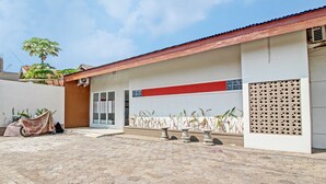 A building with a tiled patio, a garage, and potted plants.