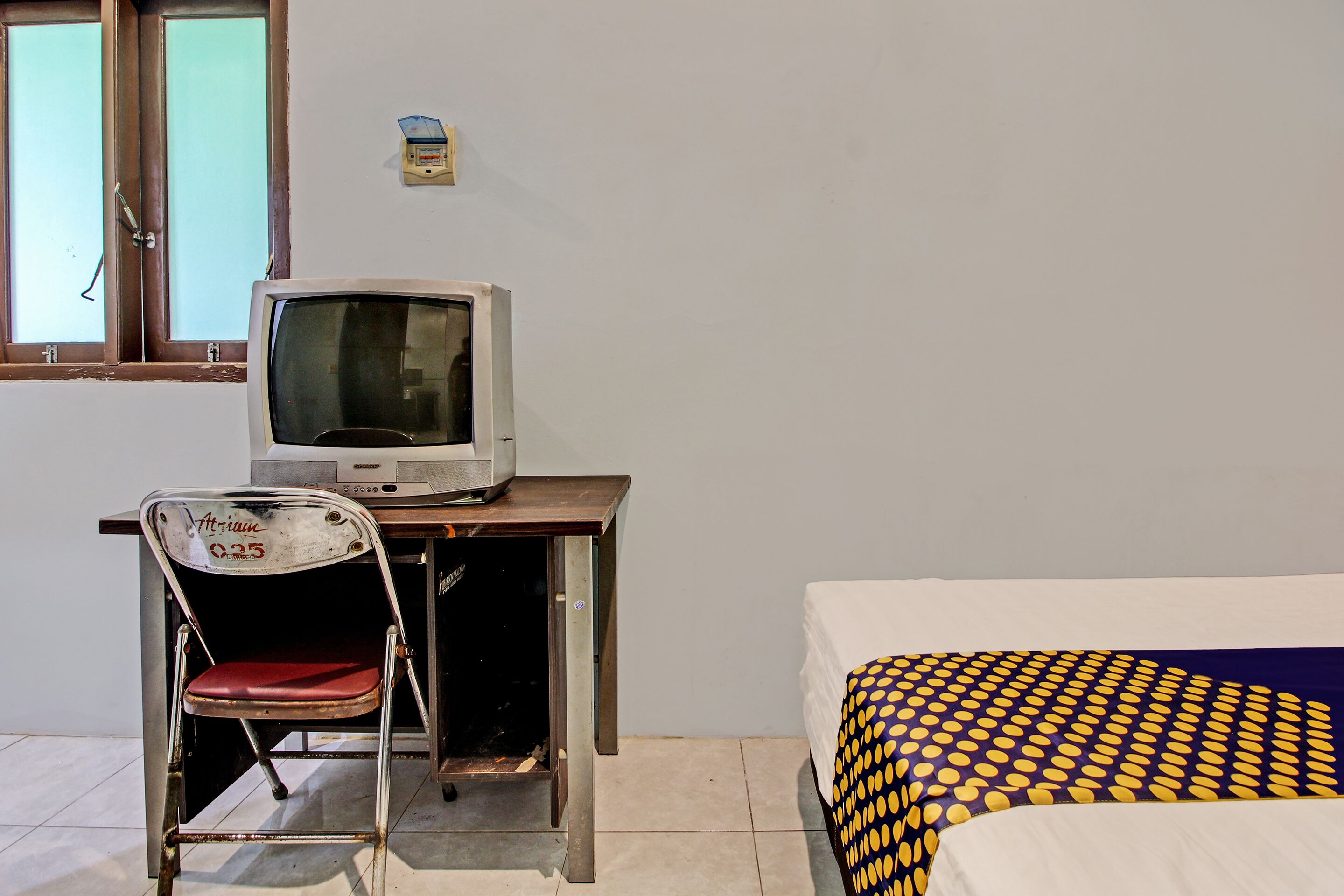 Een kamer met een bed, een bureau met een televisie en een stoel.