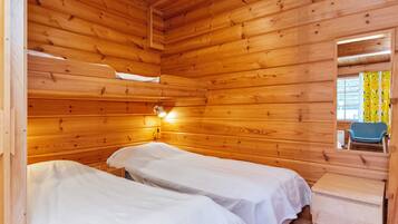 Habitación de cabaña de madera con dos camas, una mesita de noche, un espejo y una ventana con cortinas.