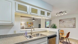 A modern kitchen with white cabinetry, a granite countertop, a dishwasher, and a ceiling fan. - Hart #206 xxxxxxxxxx (Austin)