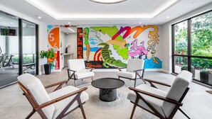 A modern lobby with a colorful mural, comfortable seating, and large windows offering a view of the outdoors.