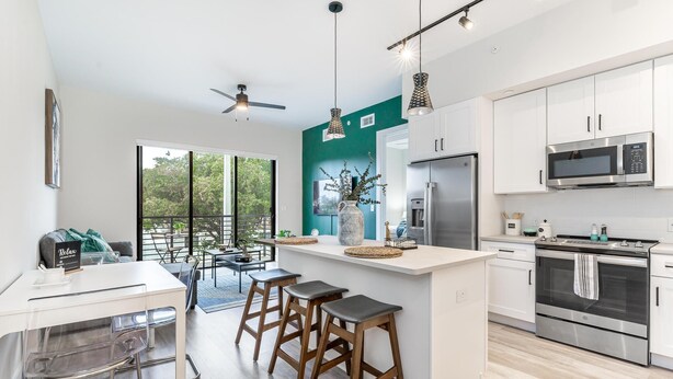 A modern kitchen with white cabinets, stainless steel appliances, and a central island with stools.