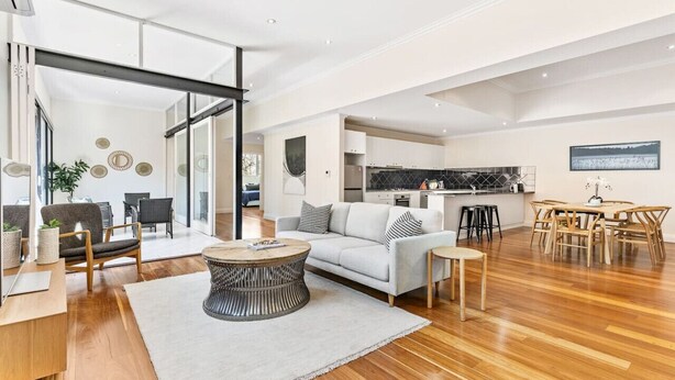 A spacious living area with a sofa, coffee table, and dining set. A kitchen is visible in the background. - Stylish Warehouse Oasis in Vibrant Darlinghurst (Darlinghurst)