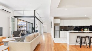 A modern kitchen with white cabinets, a black countertop, and a stainless steel refrigerator. - Stylish Warehouse Oasis in Vibrant Darlinghurst (Darlinghurst)
