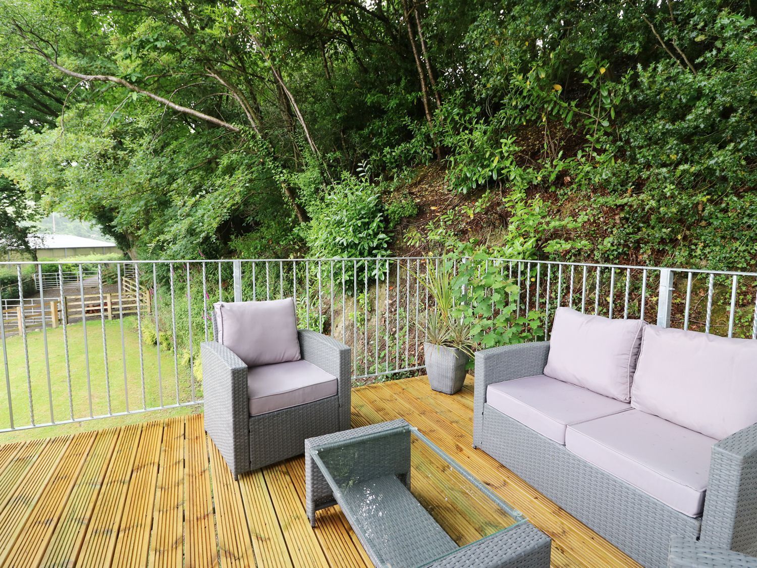 A covered outdoor seating area with wicker furniture and a wooden deck.