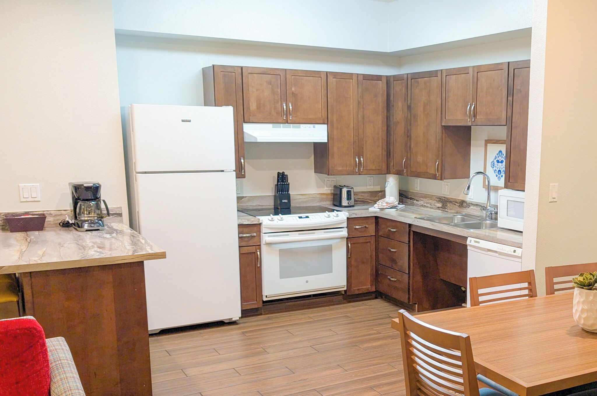 A compact kitchen with wooden cabinets, a white refrigerator, a stove, and a microwave.