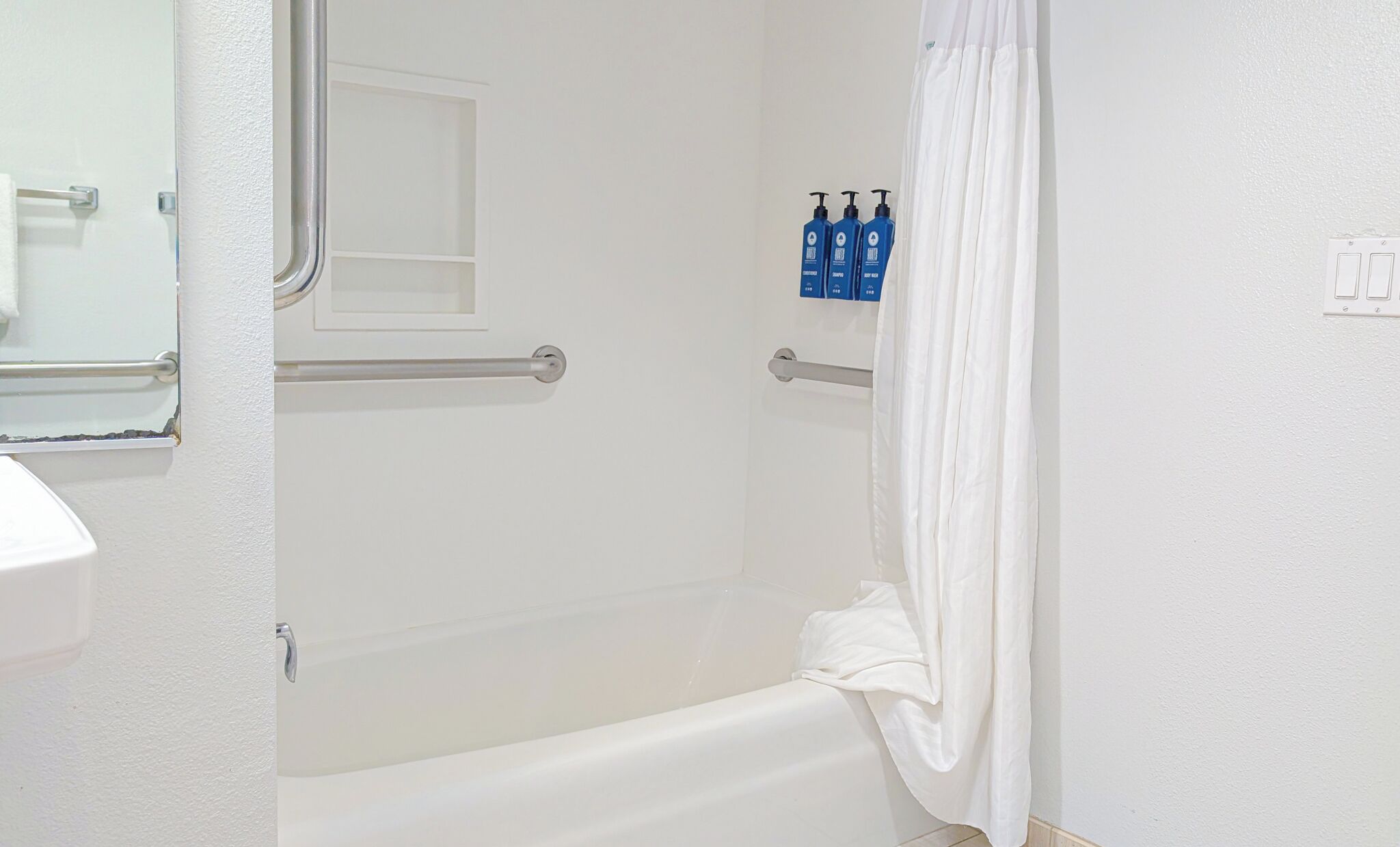 Un baño con bañera, una toalla blanca y dos botellas de champú.