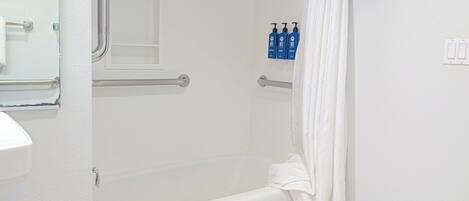 Un baño con bañera, una toalla blanca y dos botellas de champú.