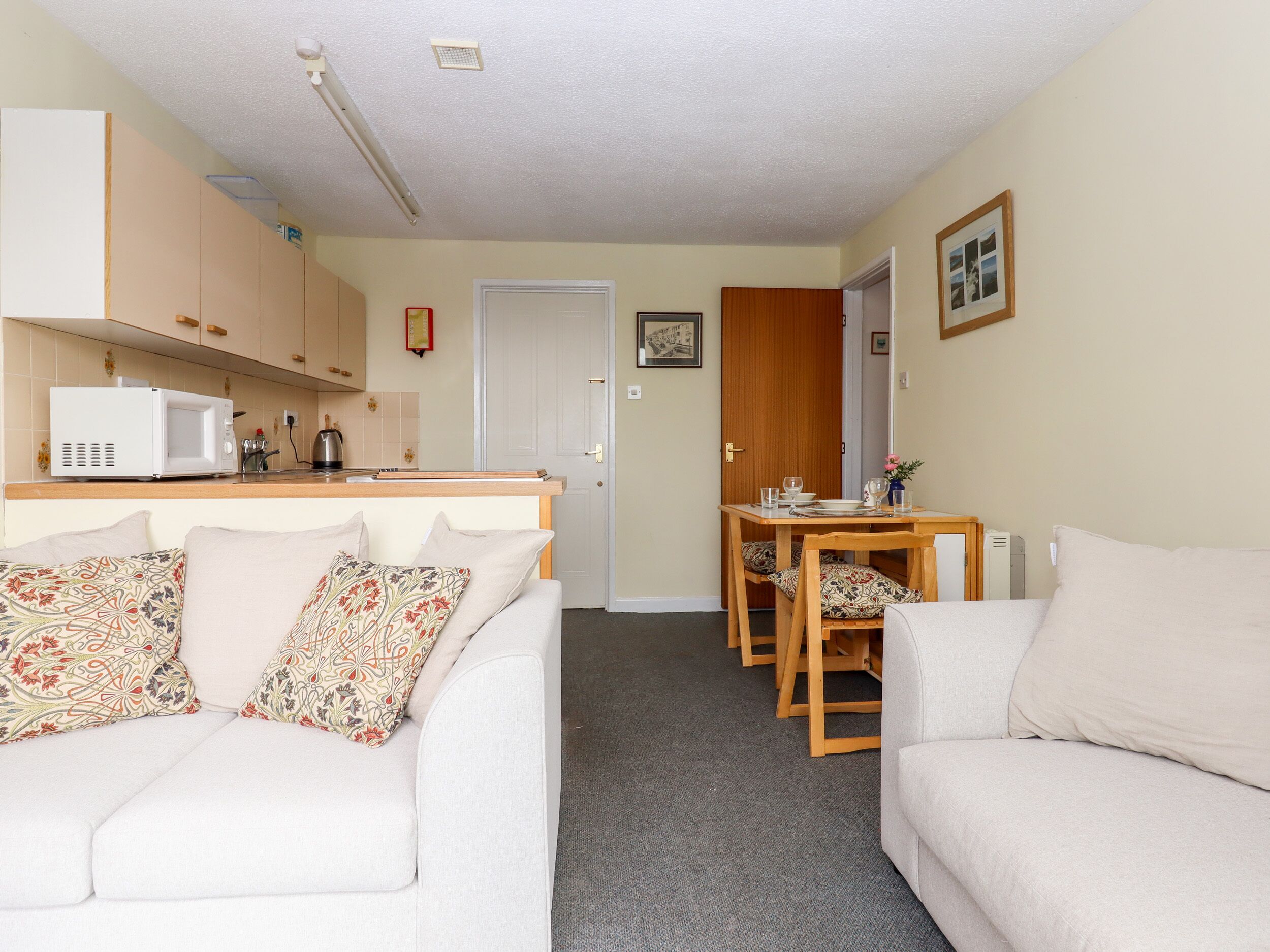 A compact living space with a kitchenette, a dining area, and a sofa with patterned cushions.