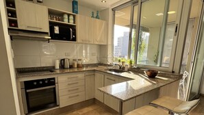 Een moderne keuken met een inbouwoven, roestvrijstalen apparatuur en een groot raam met uitzicht op de stad.