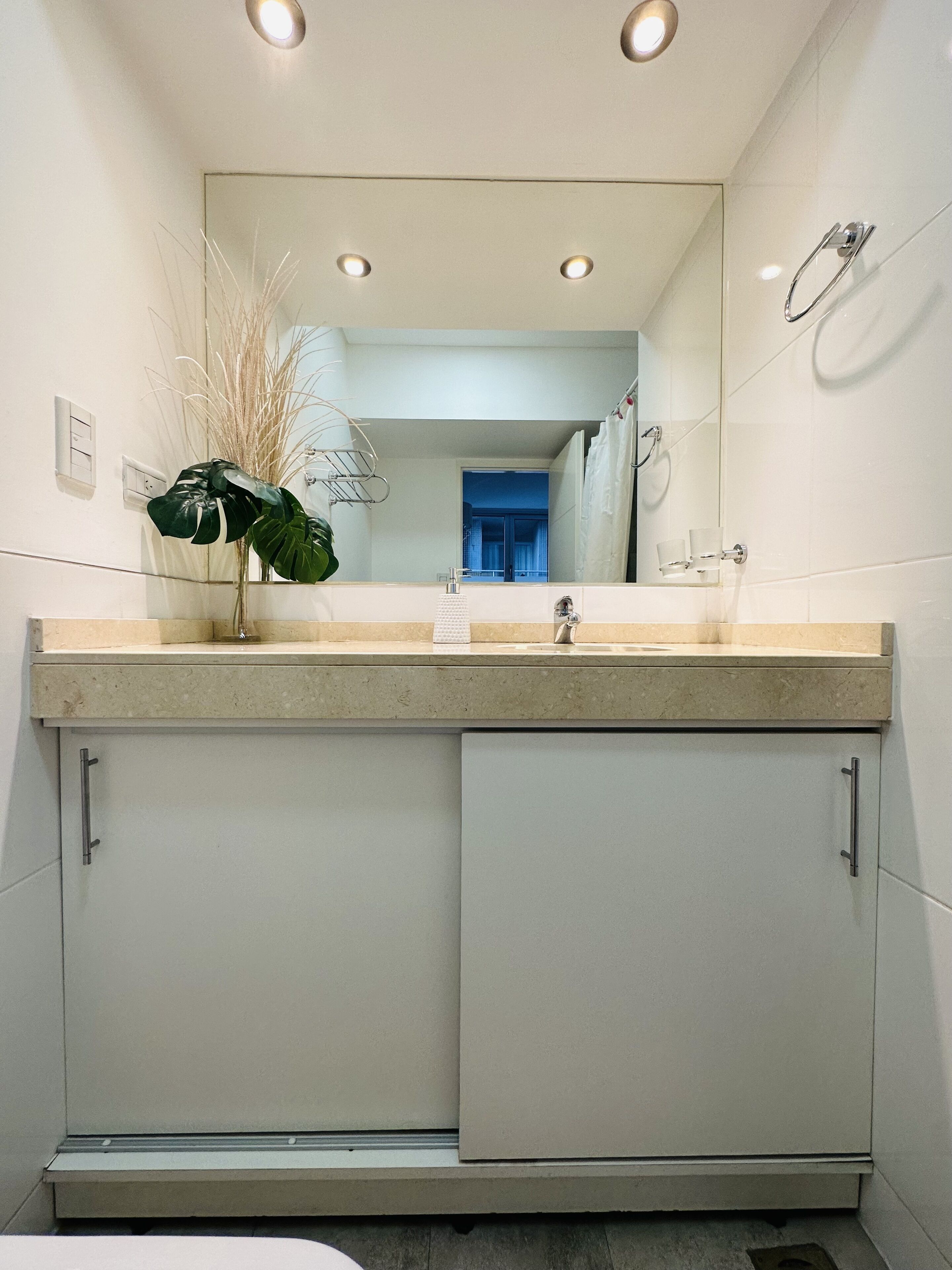 A modern bathroom with a sink, mirror, and cabinet.