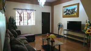 A living room with a sofa, a glass coffee table, a TV, and a painting on the wall. - Villa Elsie Resort and Hotel (General Trias)